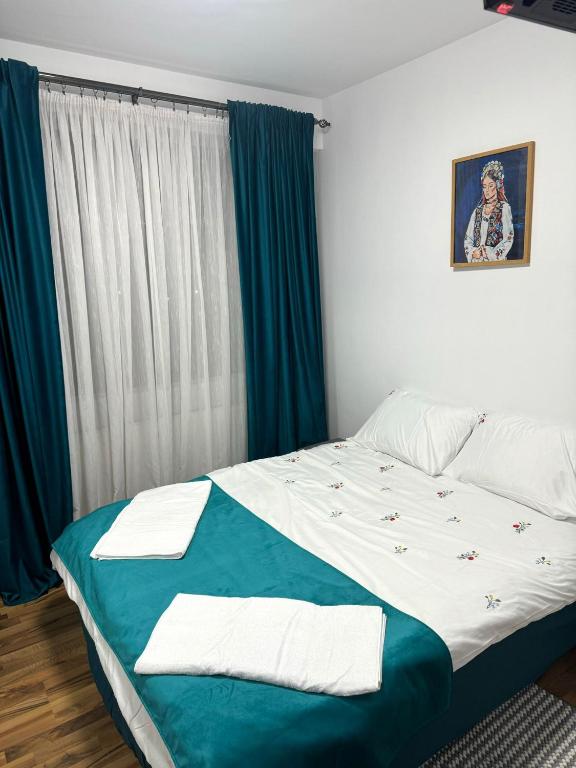 a bedroom with a bed with blue and white sheets at Apartament Central, Năsăud in Năsăud