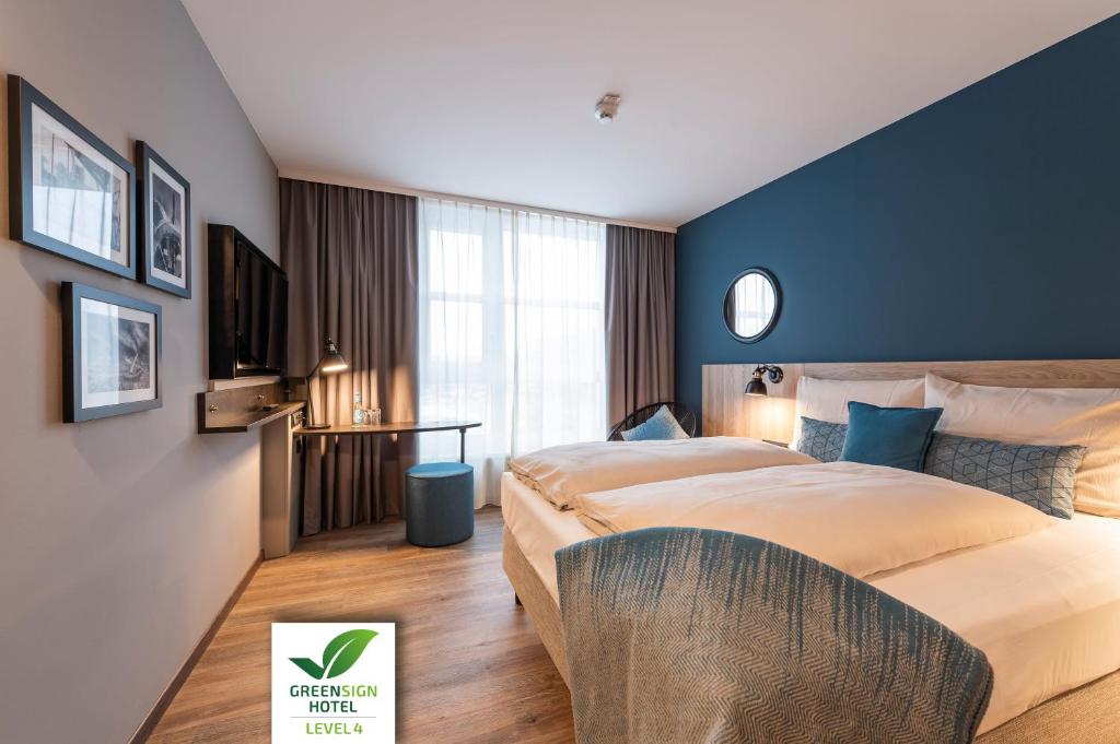 una habitación de hotel con una cama grande y paredes azules en HARBR. hotel Heilbronn, en Heilbronn