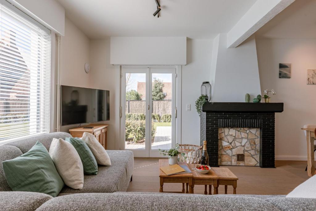 een woonkamer met een bank en een open haard bij Maison Victor in Koksijde