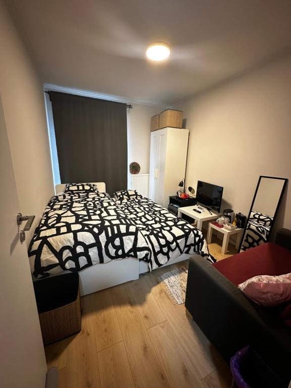 a bedroom with a bed with a black and white blanket at Alexanor Cosy Private Room in a Shared Apartment in Brussels