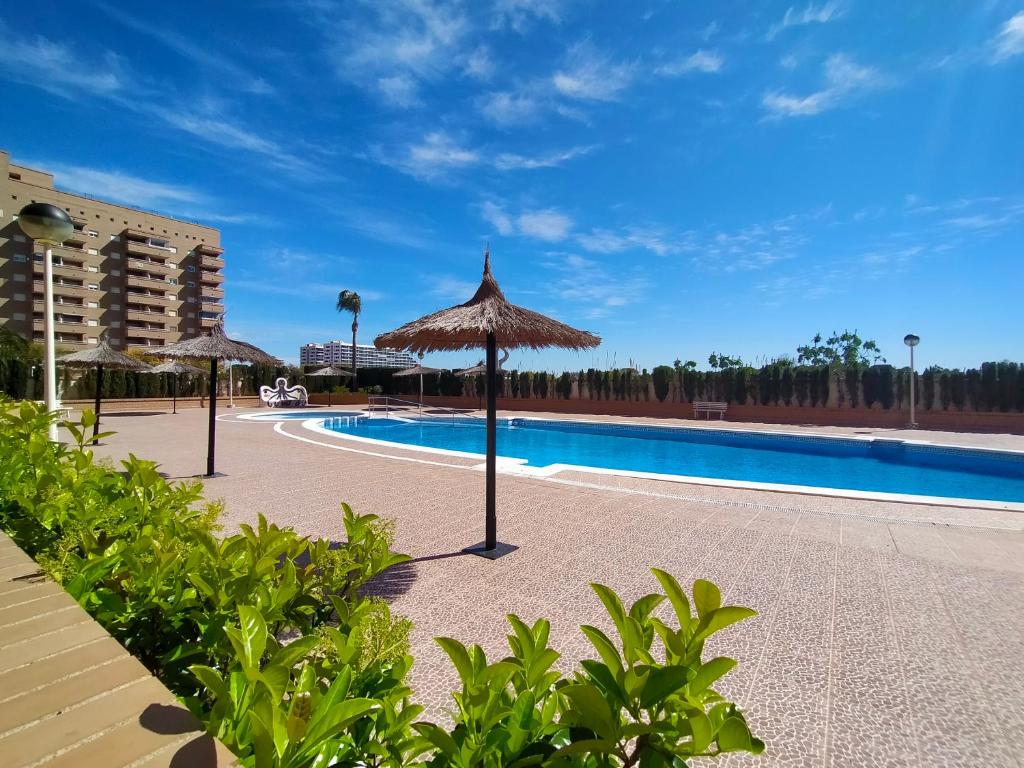 a swimming pool with umbrellas in a resort at ACV - Jardines del Mar II-2ª linea planta 1 Sur in Oropesa del Mar