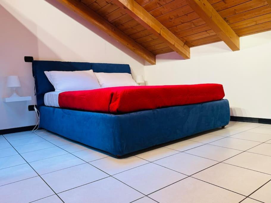 a blue bed with a red blanket in a room at La casa di Vale in Arona