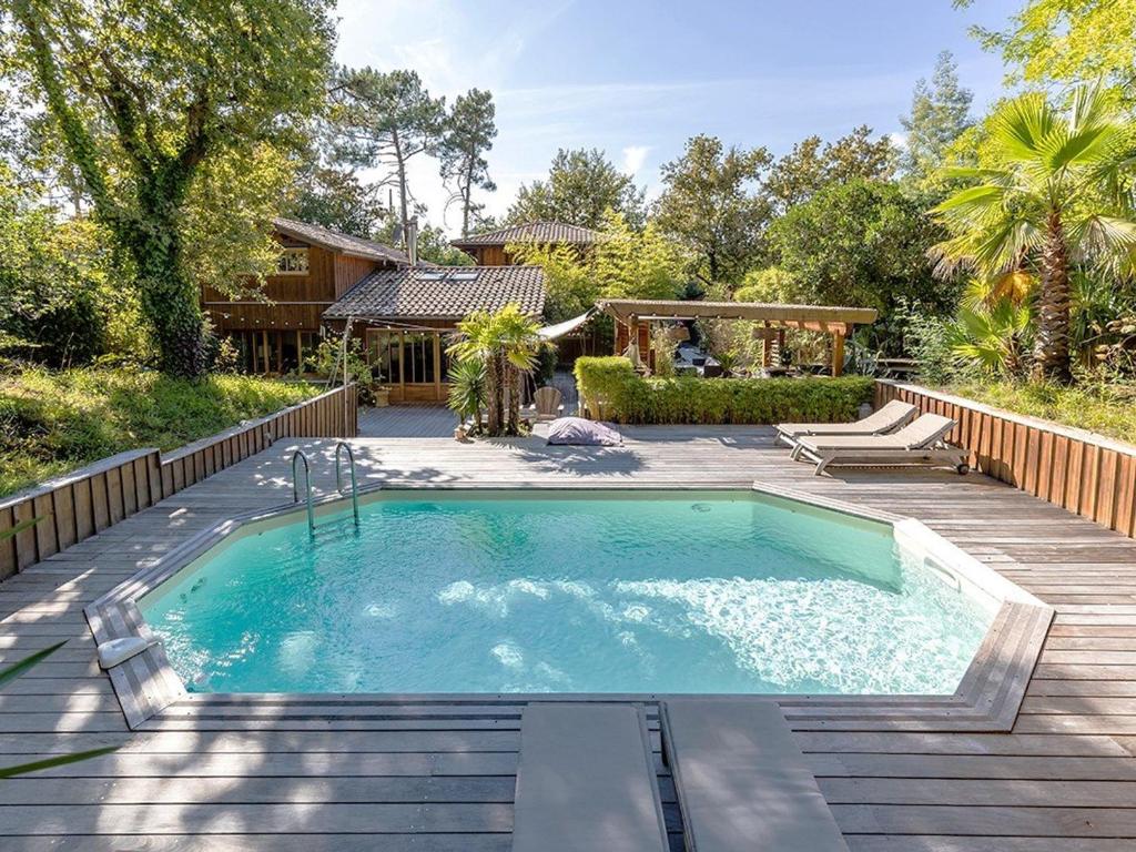 une piscine avec une terrasse en bois et une maison dans l'établissement Villa Lège-Cap-Ferret, 6 pièces, 11 personnes - FR-1-736-38, à Lège-Cap-Ferret