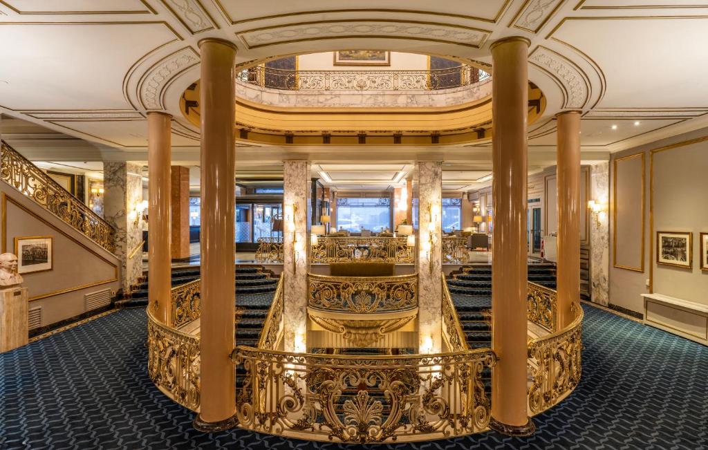 an ornate staircase in a building with a ceiling at El Avenida Palace in Barcelona