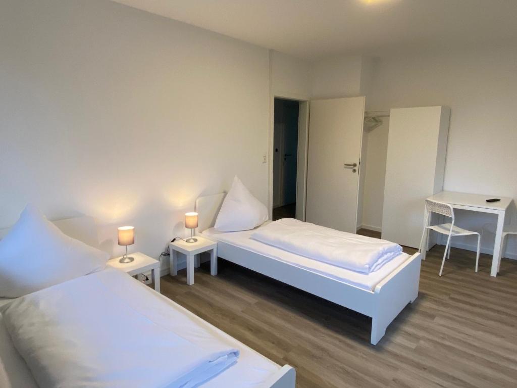 two beds in a room with two tables and two lamps at Colleen Homes Monteurwohnung Barntrup Blumenstr 1b in Barntrup