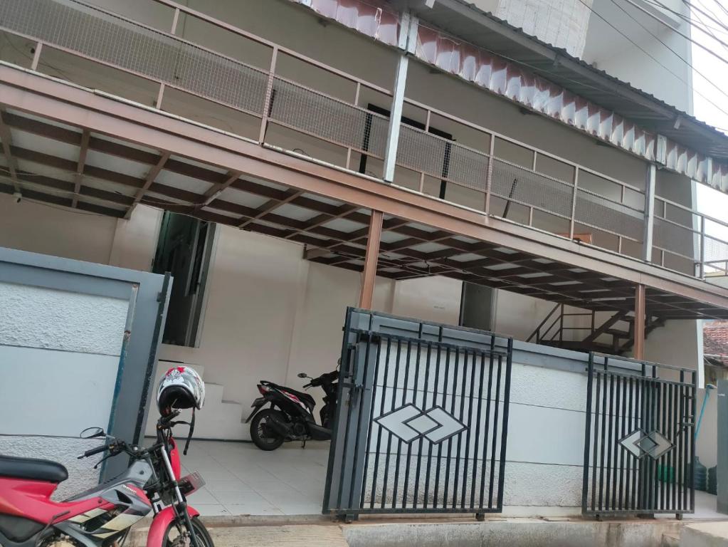 een motorfiets geparkeerd voor een gebouw met een hek bij Penginapan Wanita Putri Salju Hostel Semarang in Semarang