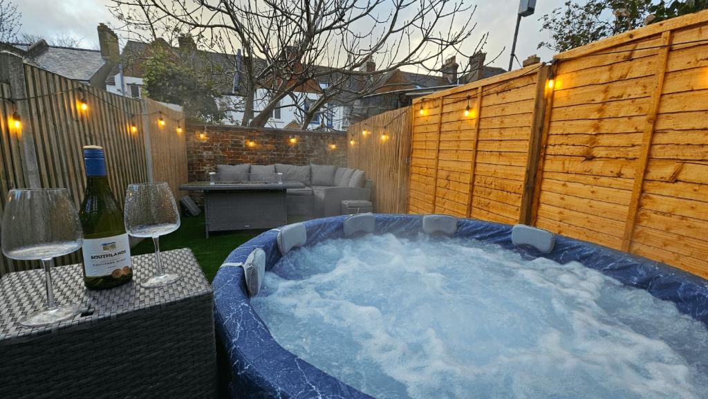 a hot tub in a backyard with a bottle of wine at City Centre with Hot Tub - 3 Bed in Kent