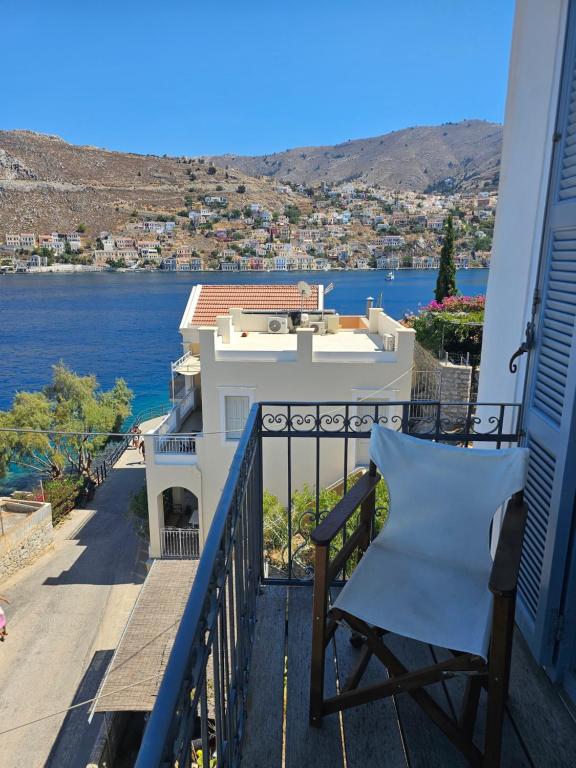 a balcony with a chair and a view of the water at The Anchor House in Symi