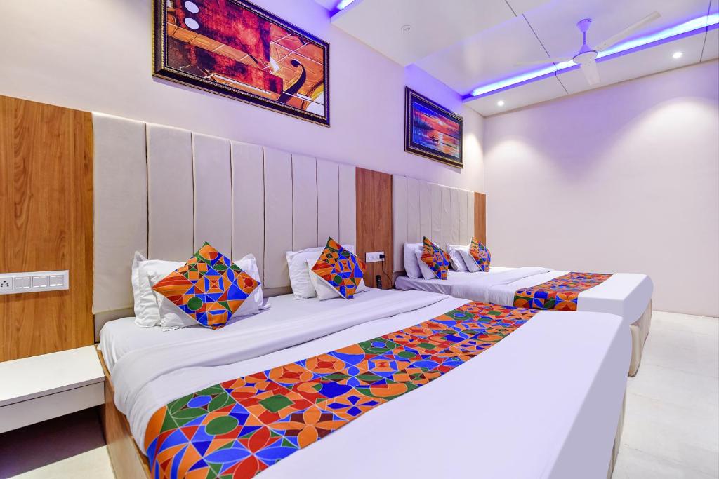 マウント・アブにあるFabHotel Prime Maya Palaceのカラフルな枕が備わるベッド2台が備わるホテルルームです。