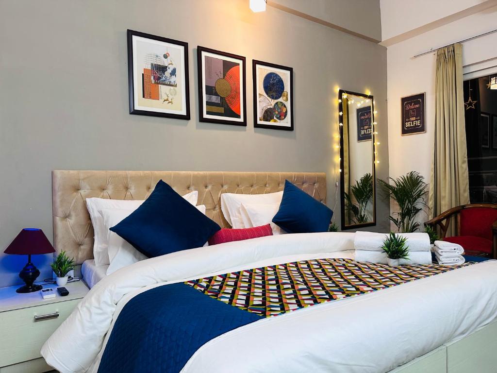 a bedroom with a large bed with blue pillows at Sapphire Skies By BuddiesHome in Greater Noida