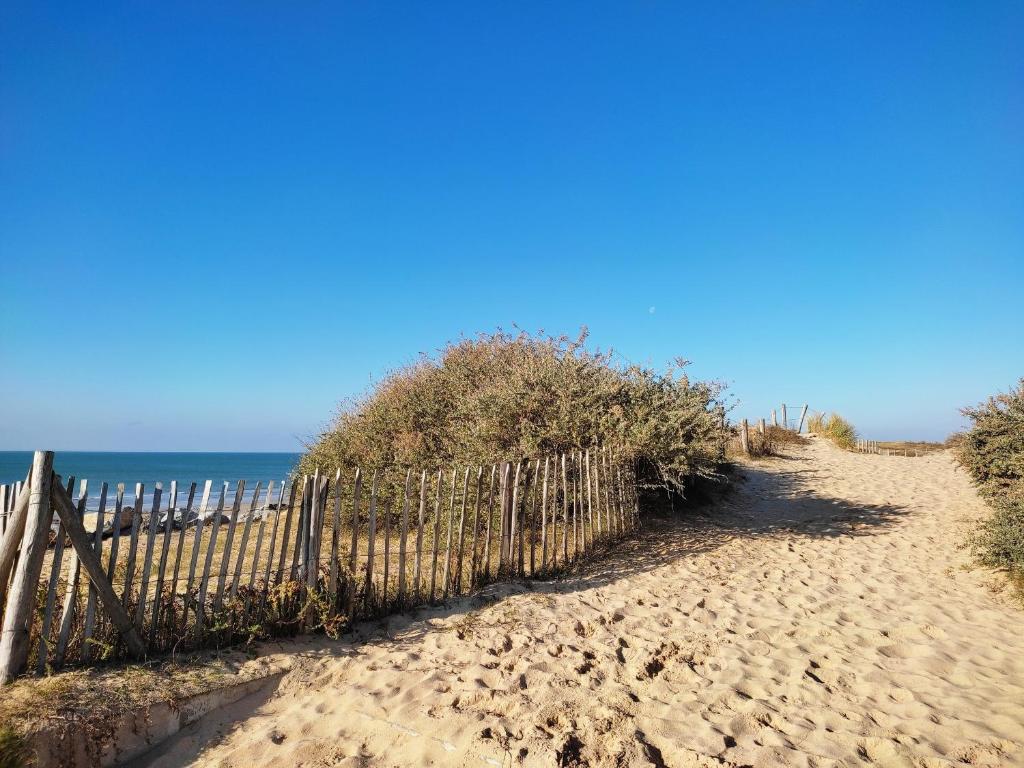 une clôture sur une plage de sable à côté de l'océan dans l'établissement Appartement Familial Proche Plage et Forêt avec Parking Privé - FR-1-652-4, à Saint-Hilaire-de-Riez