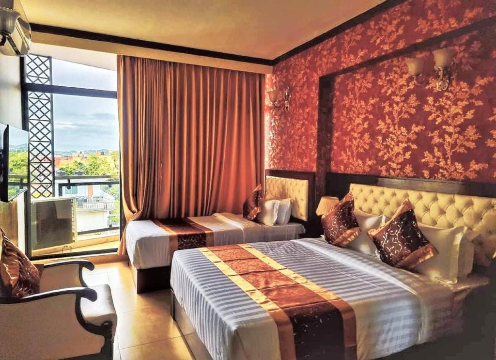 a bedroom with two beds and a large window at Hotel Crystal Rose - Sylhet in Sylhet
