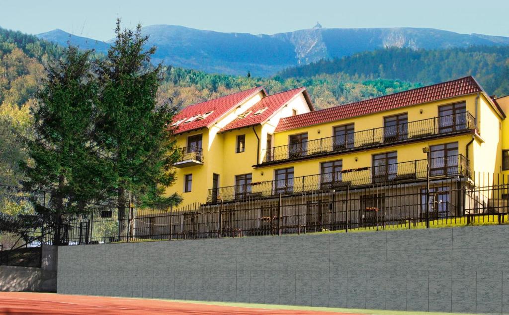 żółty budynek z czerwonymi dachami na ogrodzeniu w obiekcie Pensjonat Borowik w Jagniątkowie