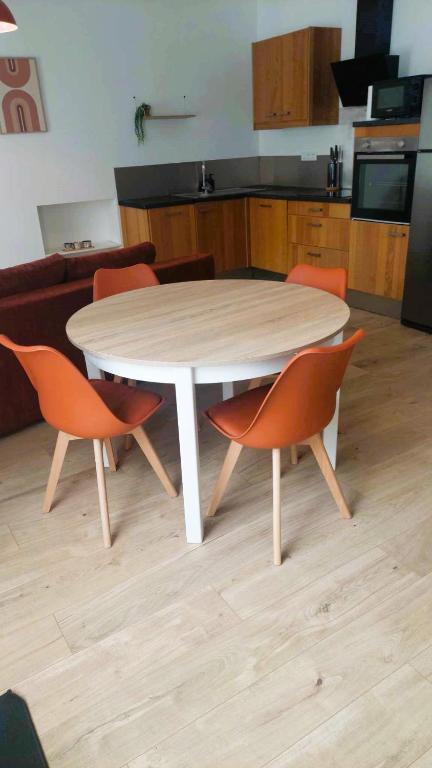 - une table blanche avec des chaises orange dans la cuisine dans l'établissement Maison de bourg - wifi - checkin autonome, à Saint-Martin-sur-Oust