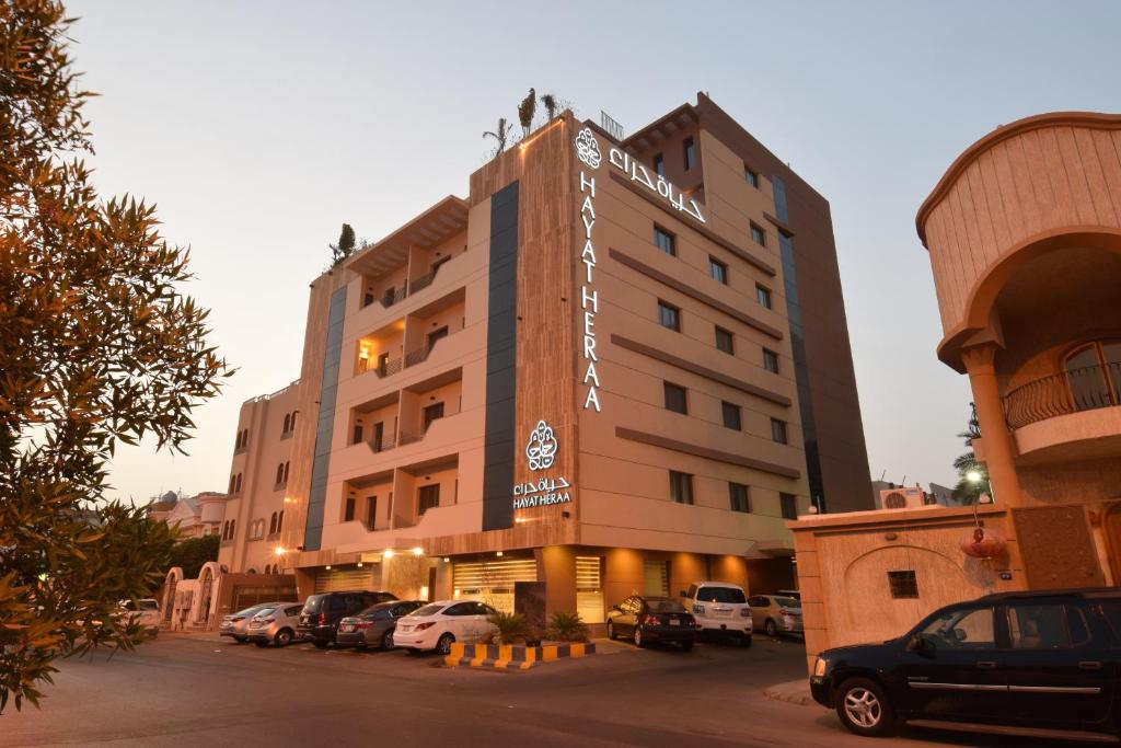 un hotel con coches estacionados en un estacionamiento en Hayat Heraa Hotel en Yeda