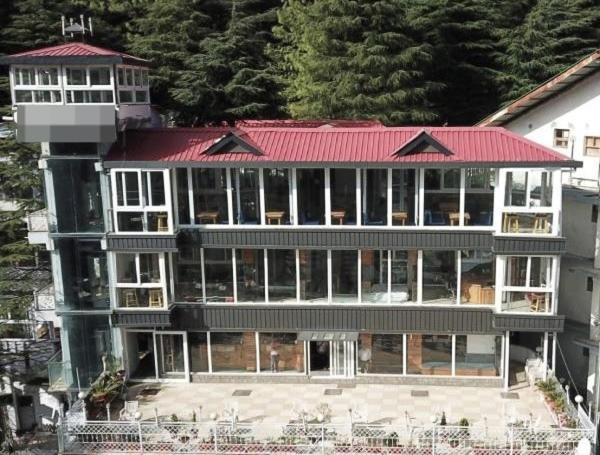 un gran edificio con techo rojo en Hotel Gandhi's Paradise, en Dharamshala