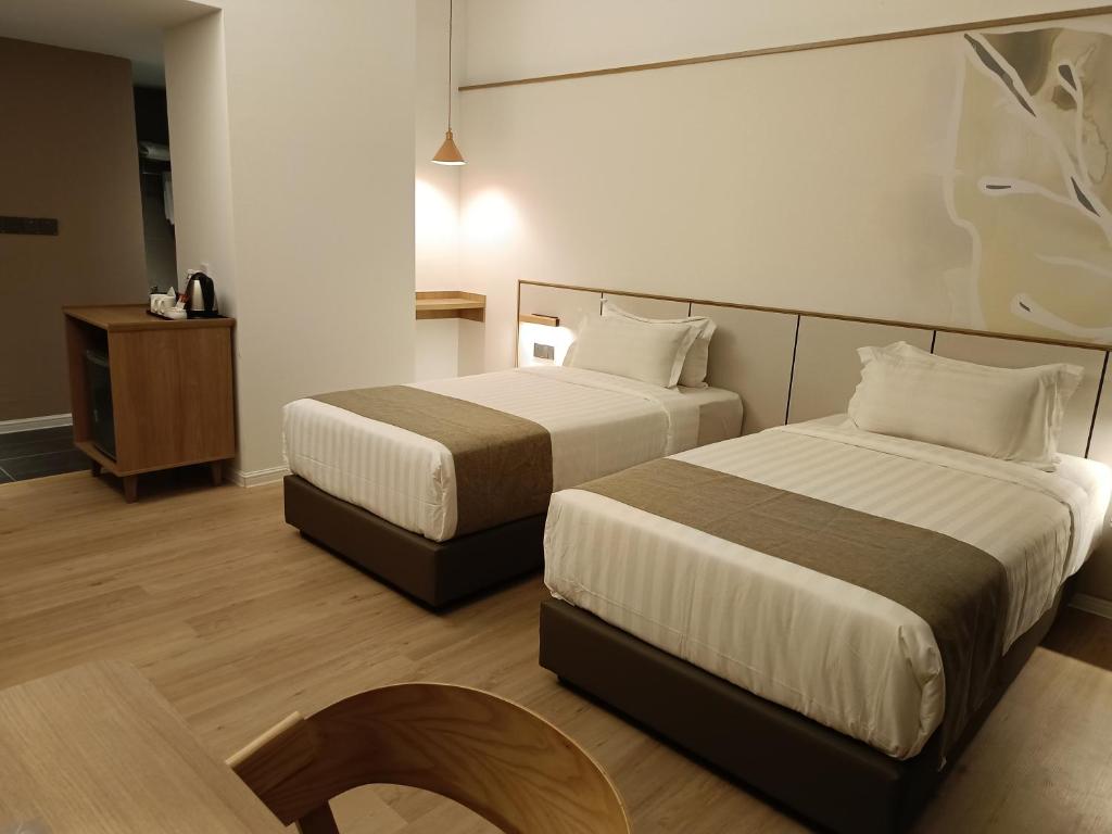 a hotel room with two beds and a chair at H Elite Design Hotel in Kota Bharu