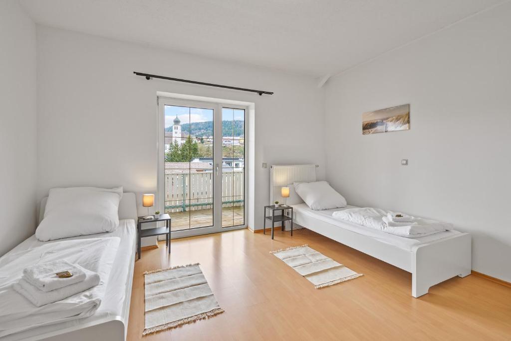 Dieses weiße Zimmer verfügt über 2 Betten und ein großes Fenster. in der Unterkunft home2stay Apartmenthaus Deggendorf Wifi Smart TV Parking*** in Deggendorf
