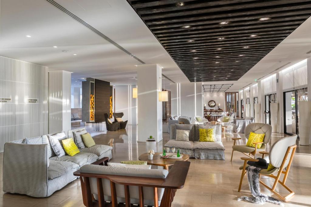 a living room with white furniture and yellow pillows at Cavo Maris Beach Hotel in Protaras