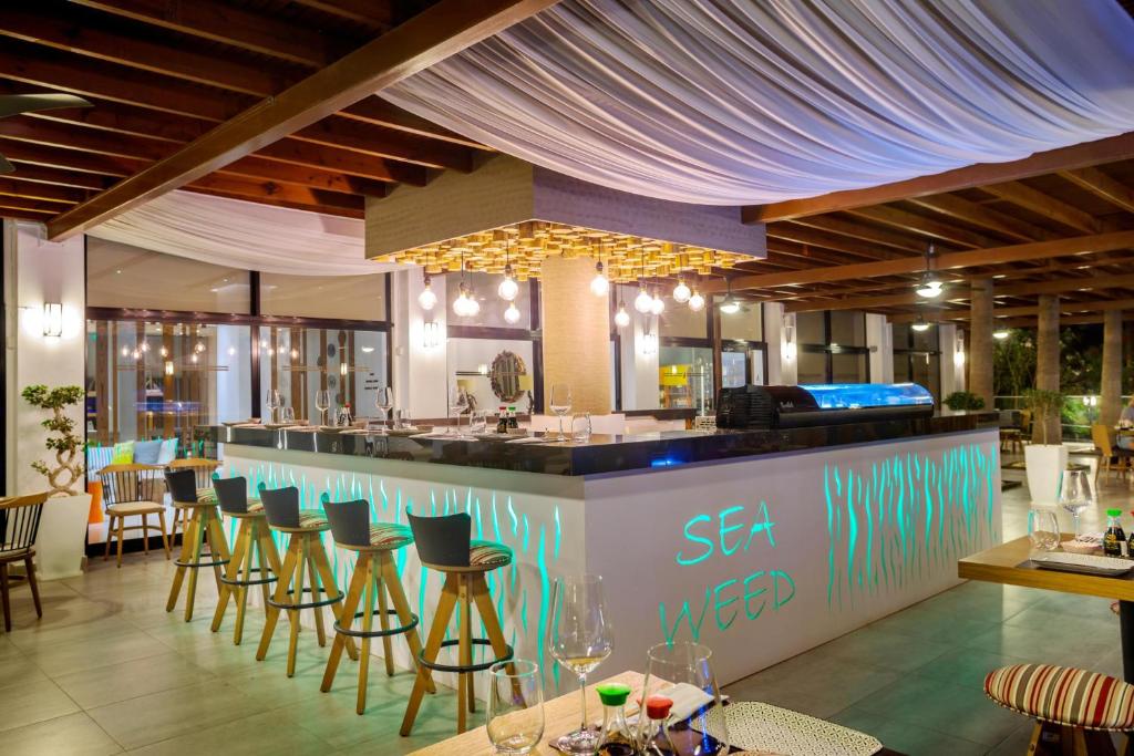 a restaurant with a bar with stools at Cavo Maris Beach Hotel in Protaras
