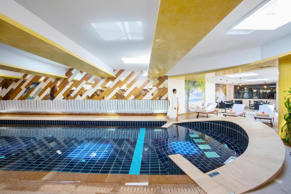 a pool in a hotel with a man standing in the background at Cavo Maris Beach Hotel in Protaras