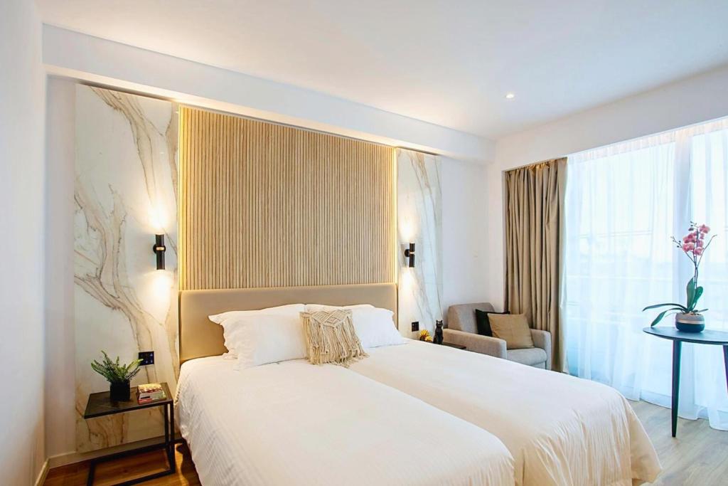 a bedroom with a large white bed and a chair at Cavo Maris Beach Hotel in Protaras