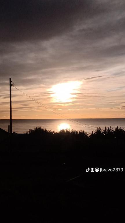 una puesta de sol sobre el océano con el sol en el cielo en HOTEL ESTRECHÓ DE MAGALLANES, en Punta Arenas