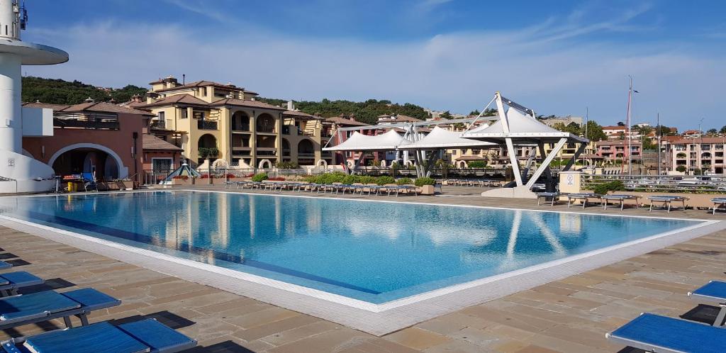a large swimming pool with blue chairs and buildings at Hotel San Rocco in Muggia