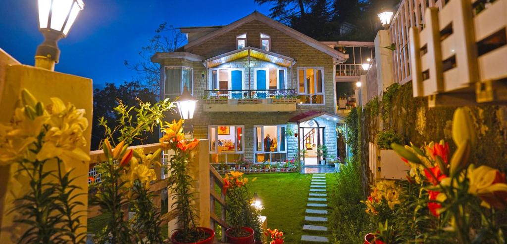 uma casa com um jardim com flores em frente em Moonlit Mansion em Shimla