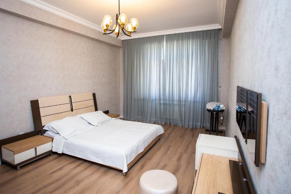 a bedroom with a white bed and a large window at Private Family apartment in Sumqayıt