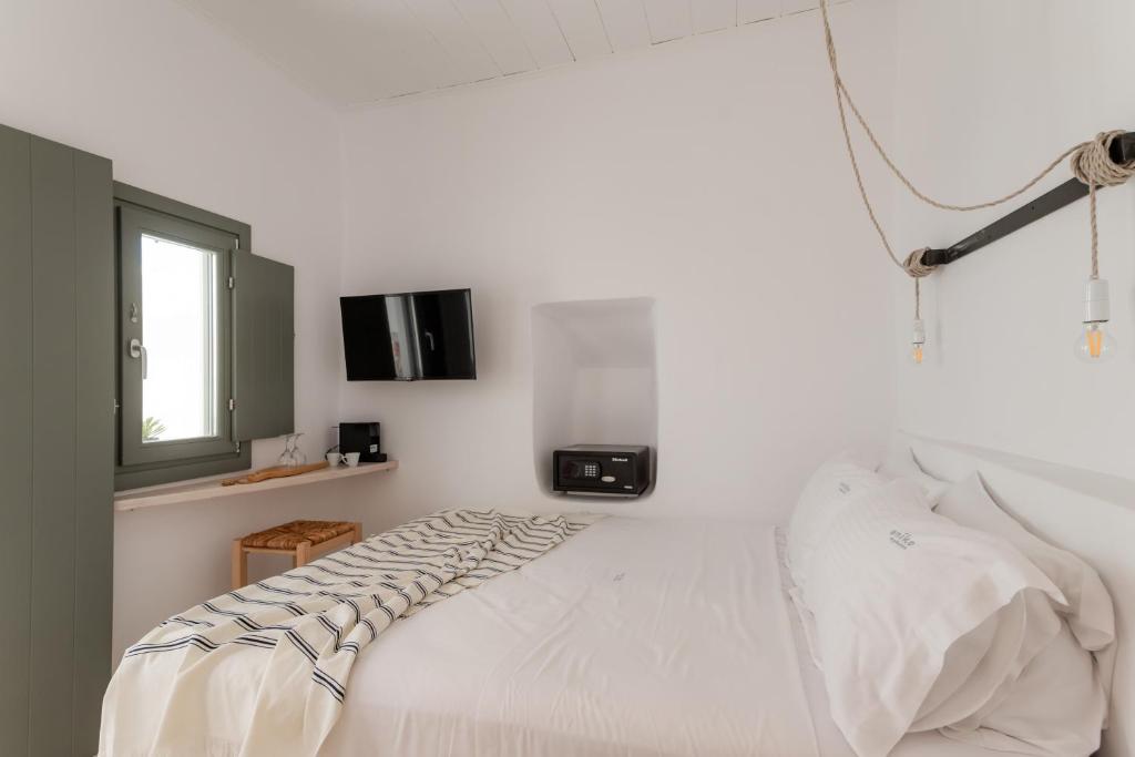 a white bedroom with a bed and a tv at aníko suites White Alley in Mikonos