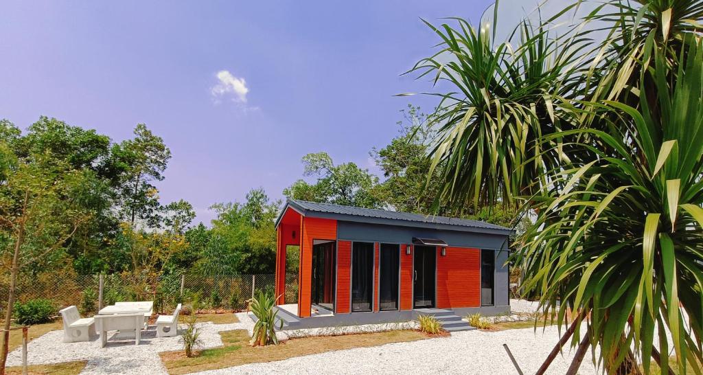 un piccolo edificio rosso e nero con sedie e alberi di Hormduk Resort a Udon Thani
