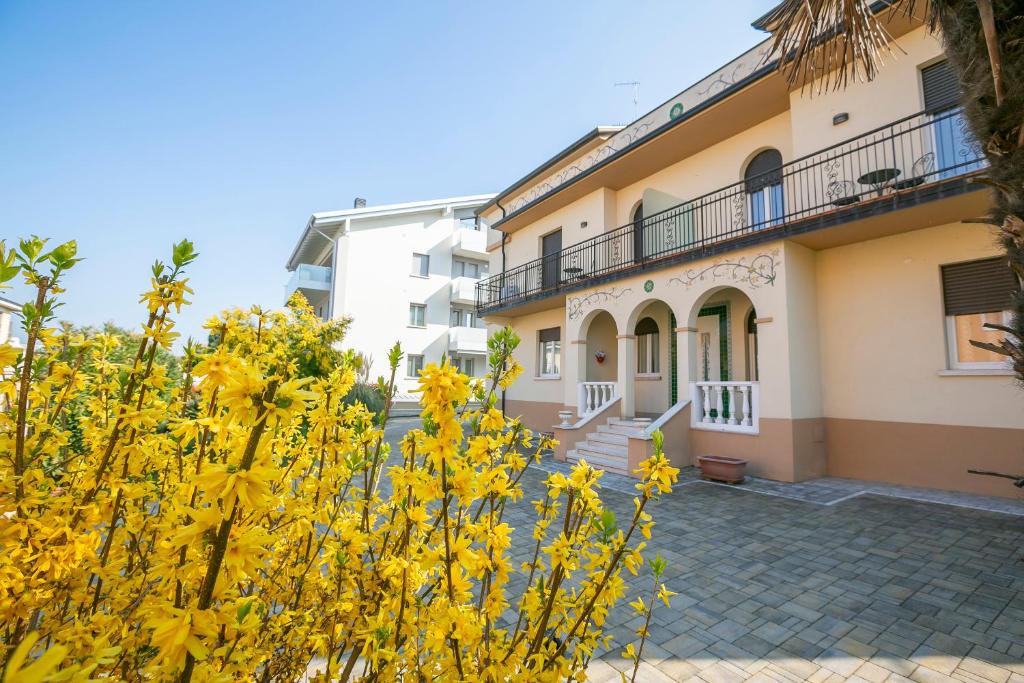 budynek z żółtymi kwiatami przed nim w obiekcie Villa Mimosa Appartamento 5 - Happy Rentals w mieście Desenzano del Garda
