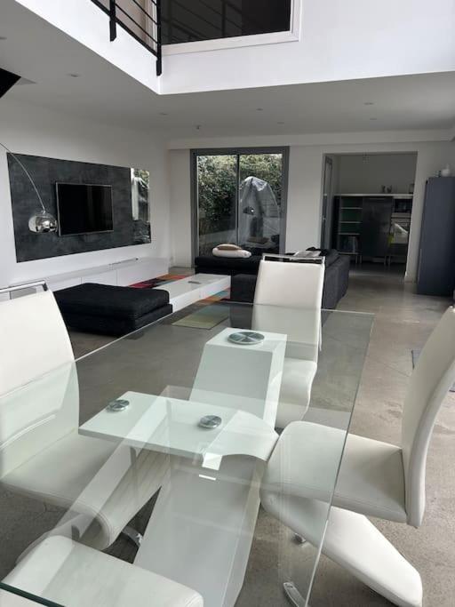 a living room with a glass table and white chairs at Maison avec piscine in Bièvres