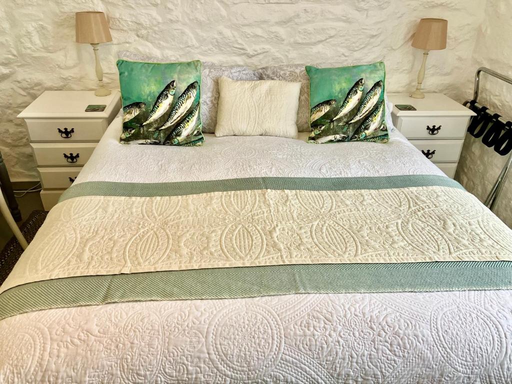 um quarto com uma cama com duas mesas de cabeceira e duas almofadas em The Old Post House B&B em St Just