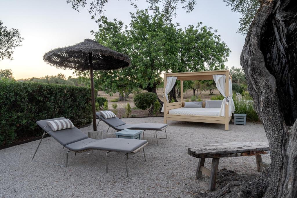a patio with a bed and chairs and an umbrella at Fazenda Nova Country House in Tavira