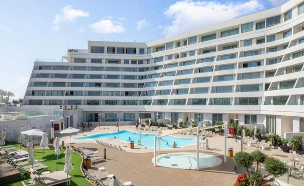 a large building with a swimming pool in front of it at סוויטות עם נוף וצמודות לים במתחם SeaSide היוקרתי עם בריכה - By SEAELO EILAT in Eilat