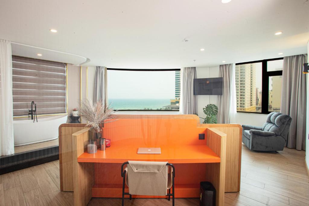 einen orangen Schreibtisch in einem Zimmer mit einem großen Fenster in der Unterkunft PĀMA Boutique Hotel & Bistro in Đà Nẵng