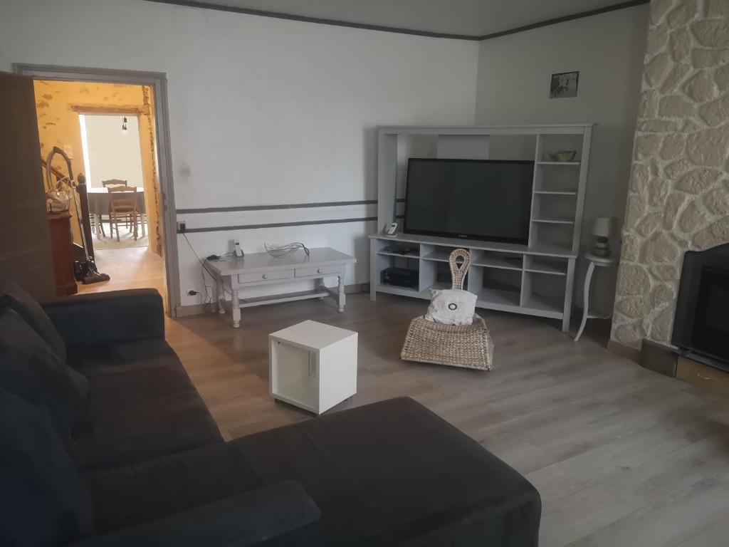 ein Wohnzimmer mit einem Sofa und einem Flachbild-TV in der Unterkunft Gîte au Gros Chêne in Saint-Amand-sur-Sèvre