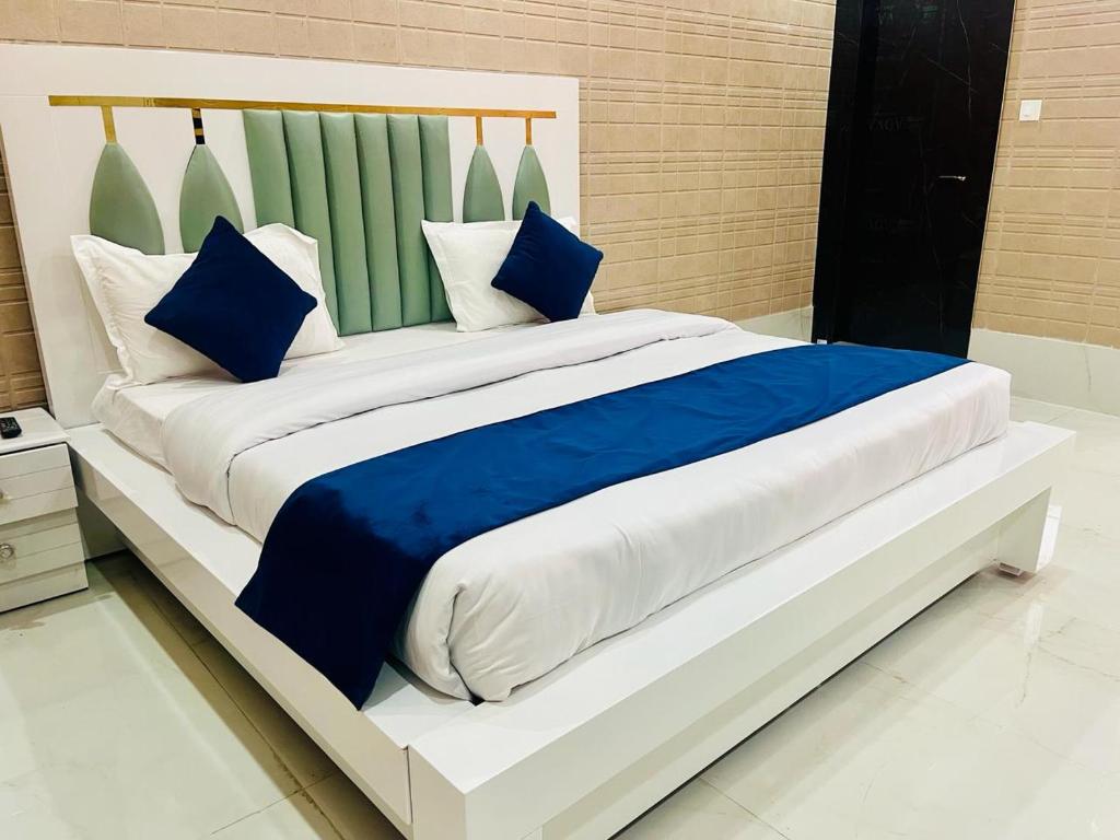 a large bed with blue and white pillows on it at As Hotel Expo Inn in Greater Noida