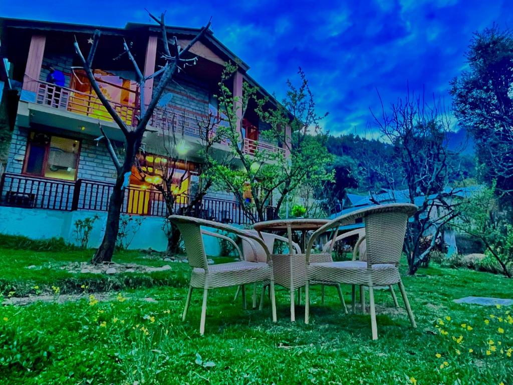 cuatro sillas sentadas en el césped frente a una casa en Nature Valley Resort Manali 2 Bedrooms luxury Cottages, en Manali