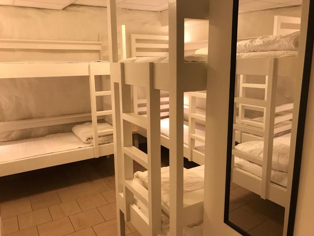 a room with white bunk beds with a mirror at Hostel Dalagatan in Stockholm