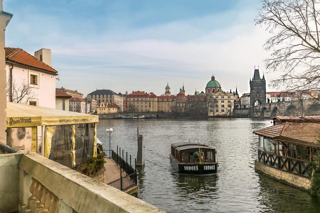 um barco num rio com uma cidade ao fundo em Residence Charles Bridge em Praga