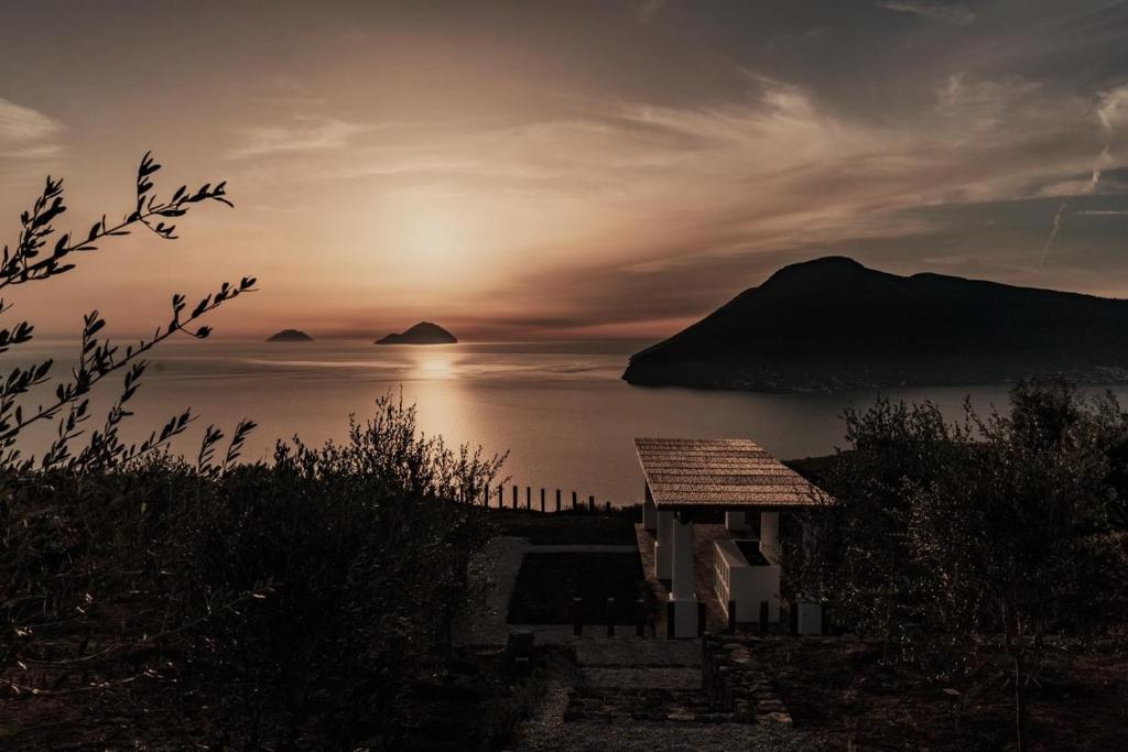 una puesta de sol sobre el océano con una casa en primer plano en Terra e Mare Casa Eoliana, en Quattro Pani