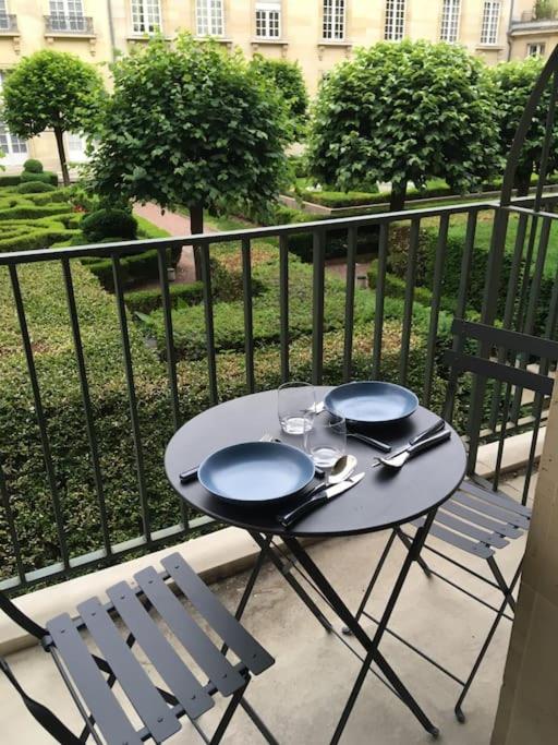 d'une table et de deux chaises sur un balcon avec une table et deux assiettes. dans l'établissement Magnifique studio coeur Marais, à Paris