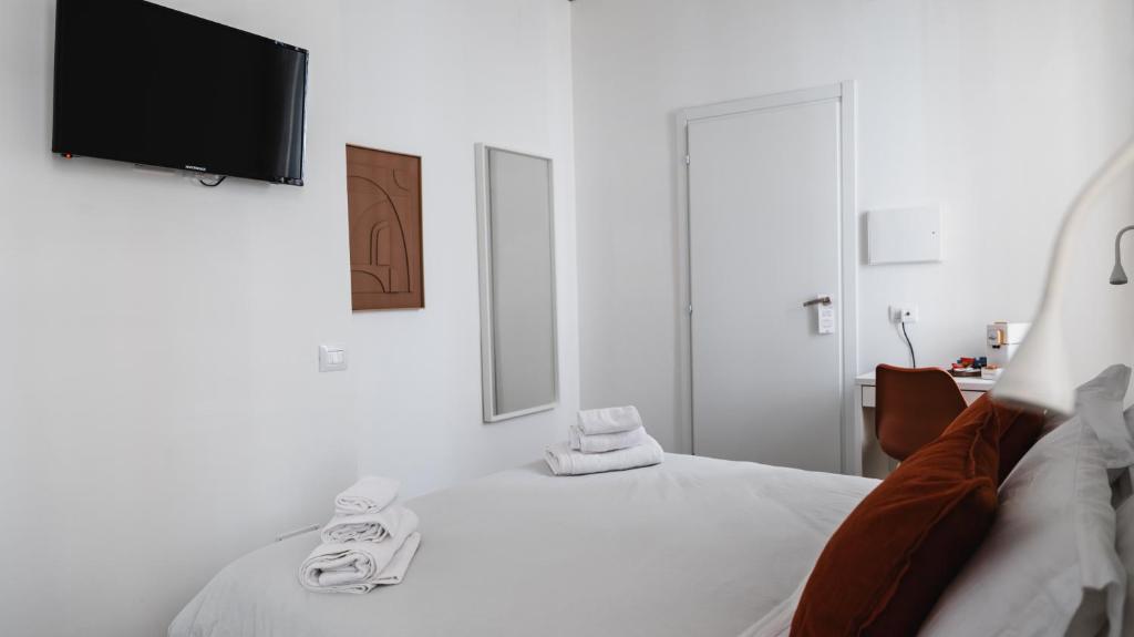 a white bedroom with a bed and a flat screen tv at Central Perk in Siracusa