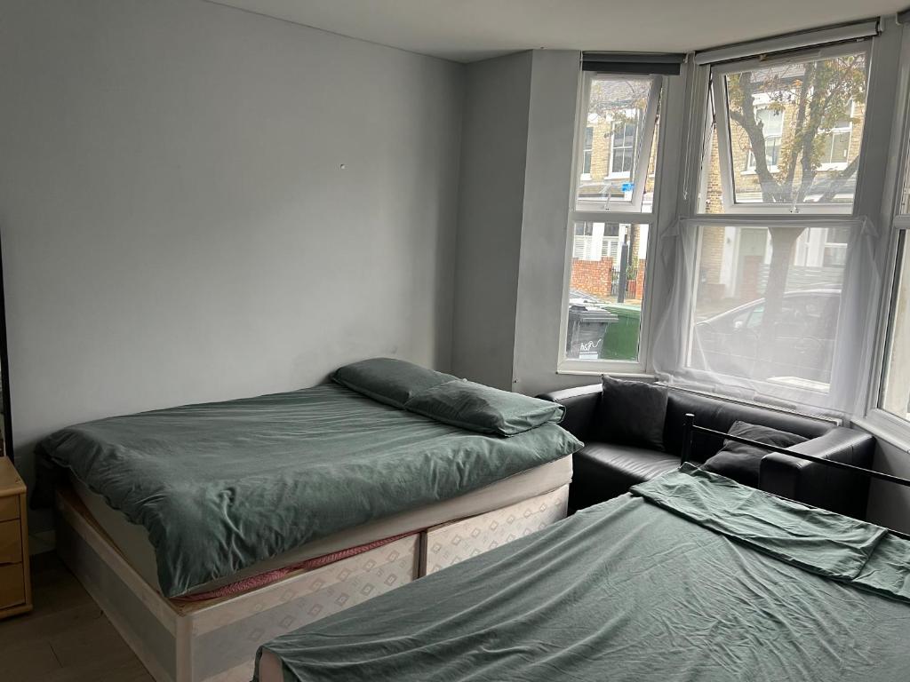 a room with two beds and a couch and a window at Sterne Street 4 Person Room in London