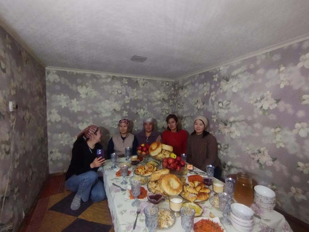 un grupo de personas sentadas alrededor de una mesa con comida en Kush, en Kochkorka