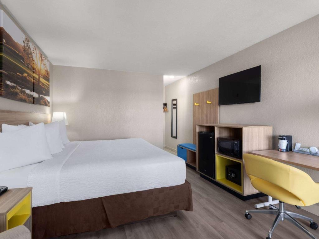 ラスベガスにあるDays Inn by Wyndham Las Vegas Airport Near the Stripの大きなベッドとデスクが備わるホテルルームです。