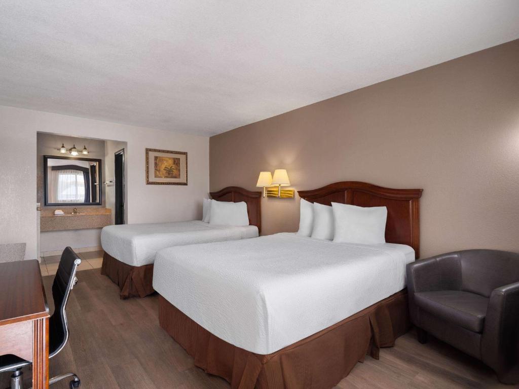 una habitación de hotel con 2 camas y una silla en Travelodge by Wyndham Tucson AZ, en Tucson